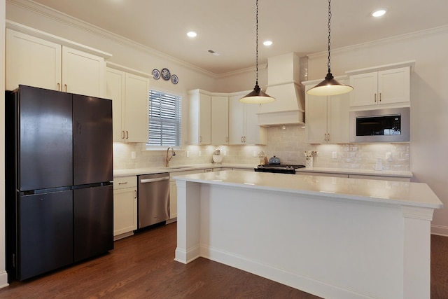 kitchen with hanging light fixtures, a center island, custom range hood, black fridge, and stainless steel dishwasher