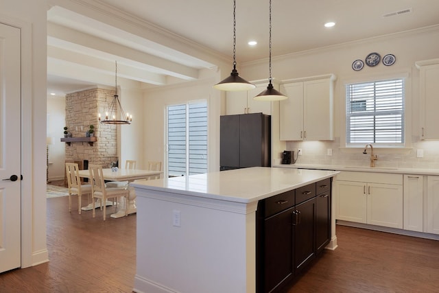 kitchen featuring white cabinetry, hanging light fixtures, sink, and a kitchen island