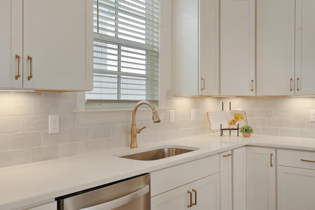 kitchen featuring white cabinetry, sink, stainless steel dishwasher, and decorative backsplash