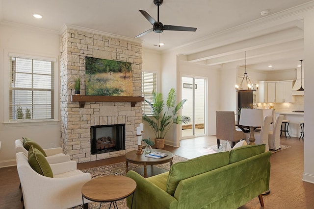 living room with a fireplace, ornamental molding, ceiling fan with notable chandelier, and hardwood / wood-style floors