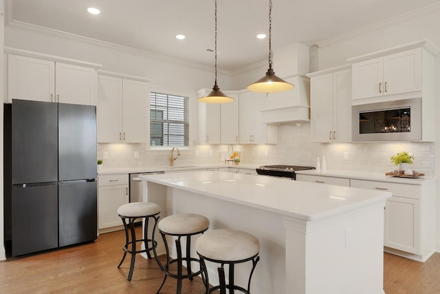 kitchen featuring white cabinetry, stainless steel appliances, a center island, sink, and crown molding