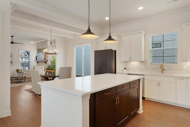 kitchen featuring white cabinets, refrigerator, decorative light fixtures, a center island, and sink