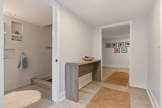 bathroom with built in shelves and wood-type flooring