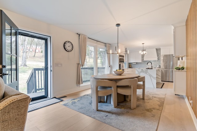 dining room featuring a chandelier, sink, and light hardwood / wood-style flooring