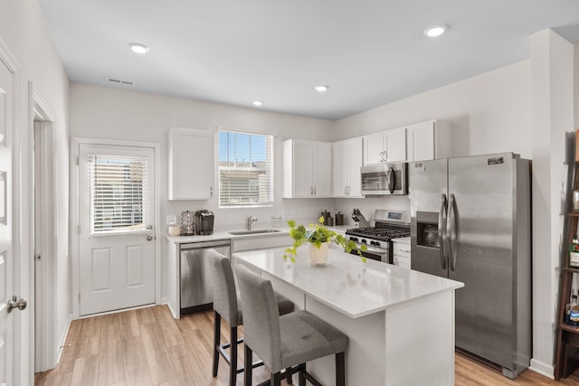 kitchen featuring sink, appliances with stainless steel finishes, a center island, white cabinets, and light wood-type flooring