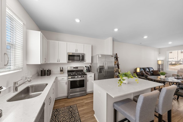 kitchen featuring stainless steel appliances, light stone countertops, sink, and white cabinets