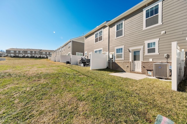 rear view of property featuring central AC unit and a yard