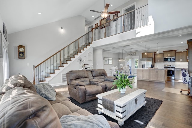 living room featuring dark wood-type flooring, ceiling fan, and a high ceiling