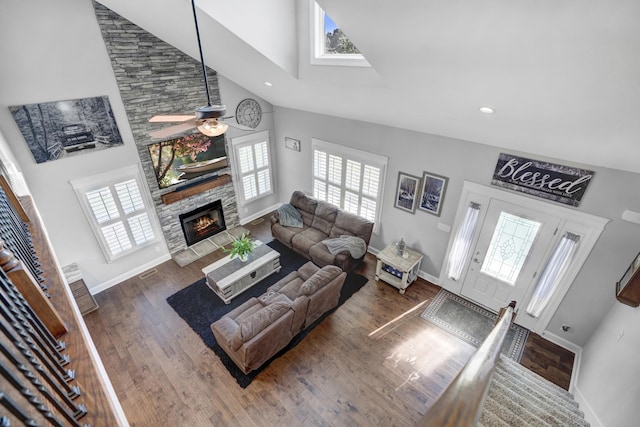 living room featuring a stone fireplace, plenty of natural light, high vaulted ceiling, and dark hardwood / wood-style floors