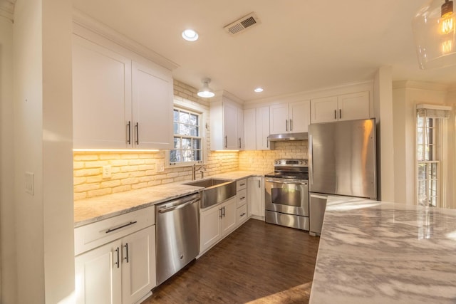 kitchen with white cabinetry, appliances with stainless steel finishes, sink, and light stone counters