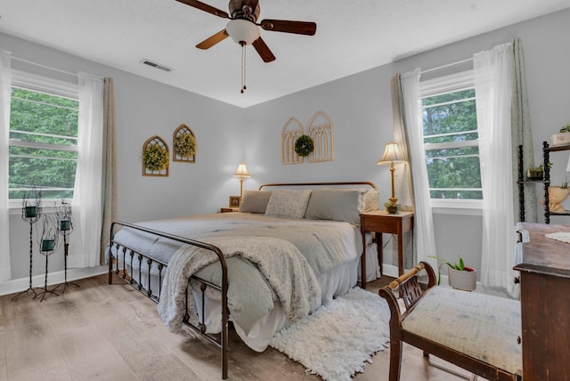 bedroom featuring multiple windows, hardwood / wood-style floors, and ceiling fan