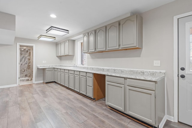 kitchen with gray cabinets, sink, and light hardwood / wood-style flooring