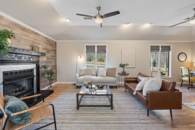 living room featuring a tiled fireplace, wood-type flooring, ceiling fan, and wood walls