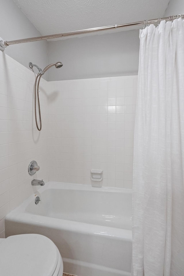 bathroom with shower / bath combination with curtain, toilet, and a textured ceiling