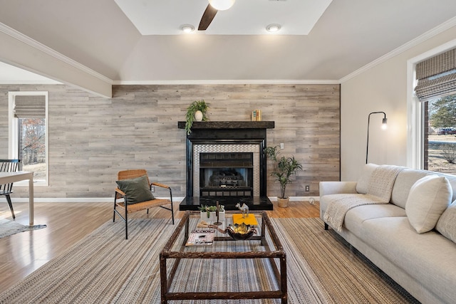 living room featuring hardwood / wood-style flooring, a tile fireplace, ceiling fan, and wood walls