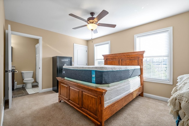 bedroom featuring connected bathroom, light colored carpet, and ceiling fan