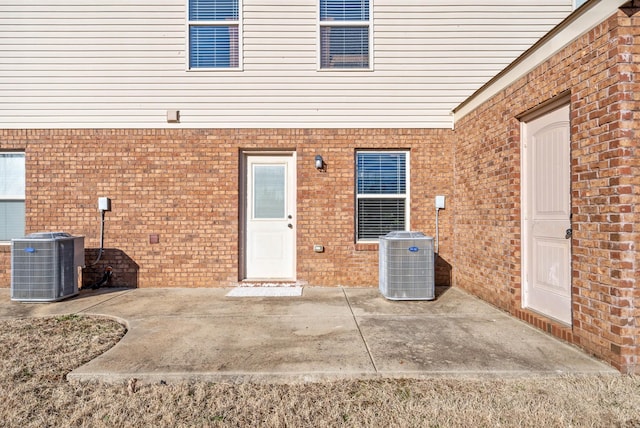 view of exterior entry featuring cooling unit and a patio area