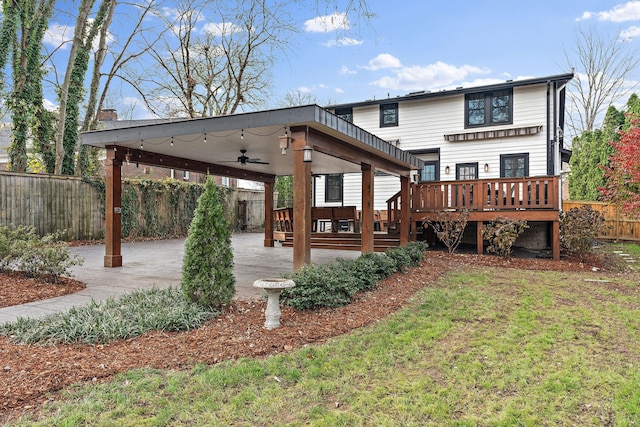 rear view of house with a wooden deck, ceiling fan, and a lawn