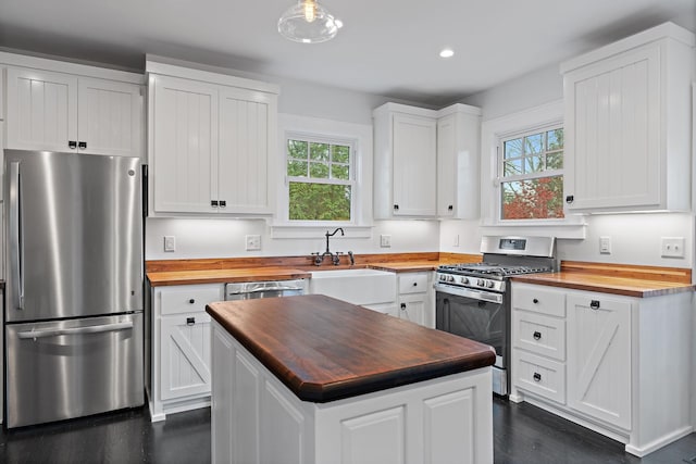 kitchen featuring butcher block counters, white cabinetry, a center island, and appliances with stainless steel finishes