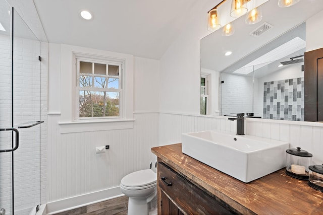 bathroom featuring toilet, a shower with shower door, vanity, vaulted ceiling with skylight, and hardwood / wood-style floors