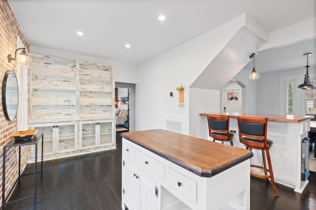 kitchen with decorative light fixtures, dark wood-type flooring, a center island, and white cabinets