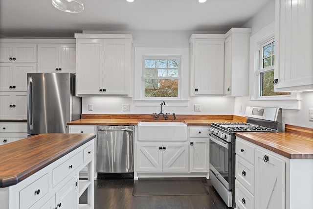 kitchen with sink, white cabinetry, wooden counters, appliances with stainless steel finishes, and dark hardwood / wood-style floors