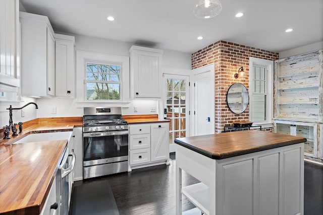 kitchen featuring white cabinetry, a center island, butcher block countertops, and stainless steel gas stove