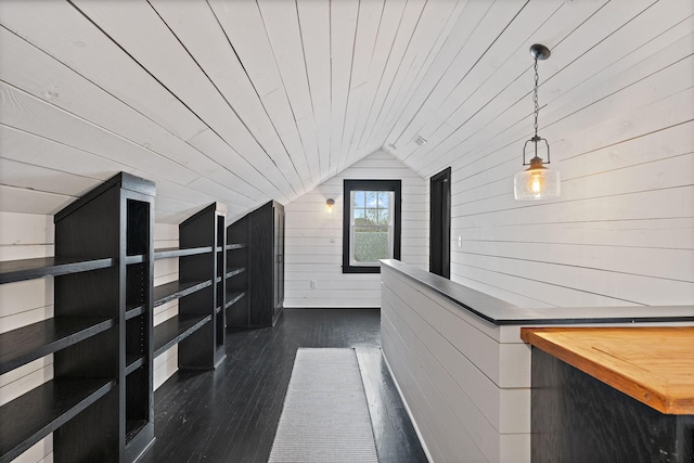 interior space with vaulted ceiling, dark hardwood / wood-style flooring, wood ceiling, and wooden walls