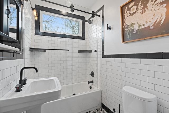 full bathroom featuring tile walls, sink, toilet, and combined bath / shower with glass door