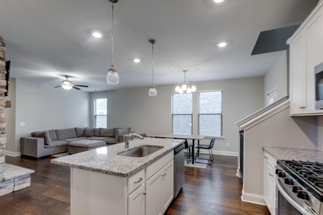 kitchen featuring an island with sink, sink, white cabinets, and light stone counters