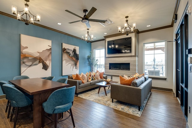 living room featuring ornamental molding, dark wood-type flooring, and ceiling fan with notable chandelier