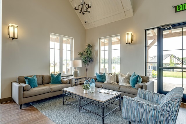 living room with a notable chandelier, hardwood / wood-style flooring, a wealth of natural light, and a high ceiling