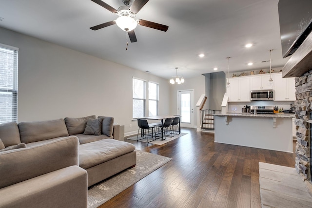 living room featuring dark hardwood / wood-style flooring and ceiling fan with notable chandelier