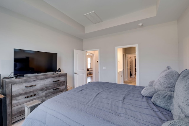 bedroom with a raised ceiling and connected bathroom