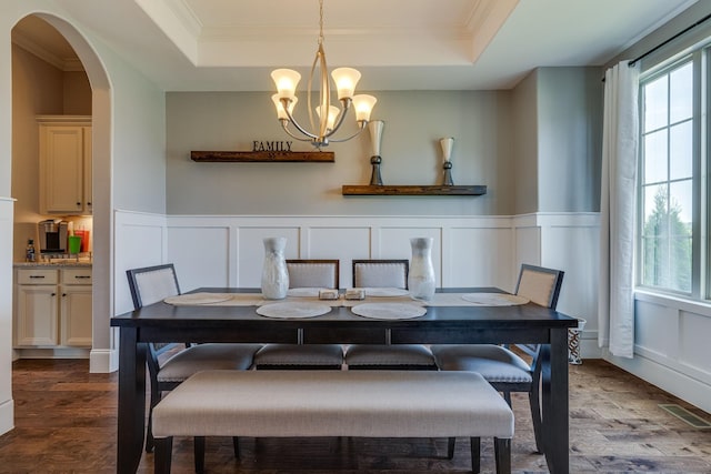 dining space with an inviting chandelier, dark hardwood / wood-style floors, a raised ceiling, and crown molding