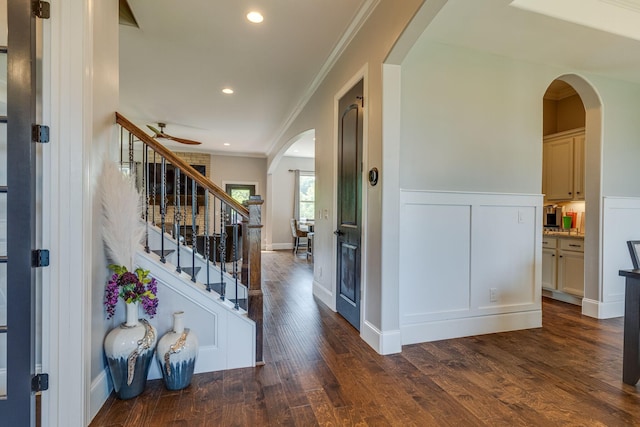 entryway with dark wood-type flooring, ornamental molding, and ceiling fan