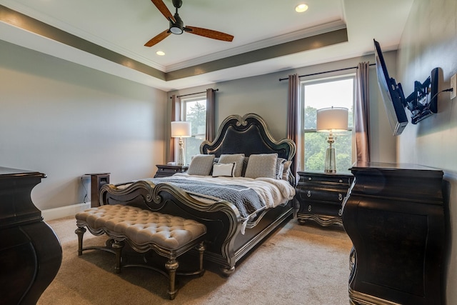 carpeted bedroom with crown molding, a tray ceiling, and ceiling fan