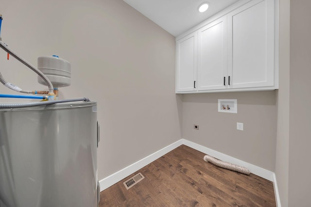 laundry room with water heater, dark hardwood / wood-style flooring, cabinets, hookup for a washing machine, and hookup for an electric dryer