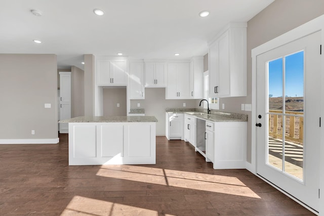 kitchen featuring a wealth of natural light, light stone countertops, white cabinets, and a kitchen island