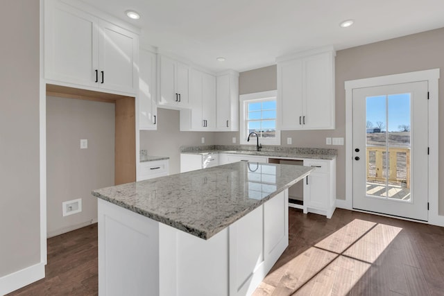 kitchen featuring dishwasher, dark hardwood / wood-style floors, light stone countertops, white cabinets, and a kitchen island