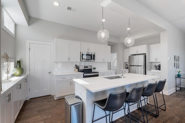 kitchen featuring white cabinetry, appliances with stainless steel finishes, a kitchen island with sink, and sink