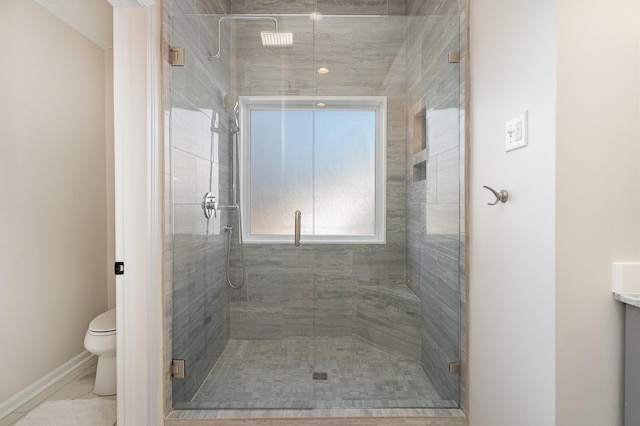 bathroom featuring a shower with door and toilet