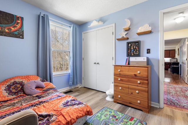 bedroom with light hardwood / wood-style floors, a closet, and a textured ceiling