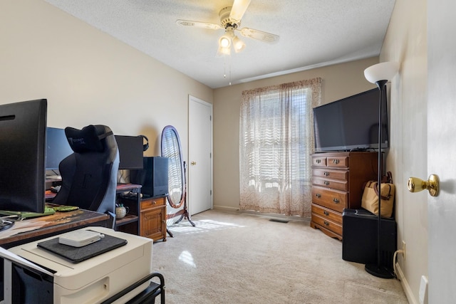 home office featuring ceiling fan, light carpet, and a textured ceiling