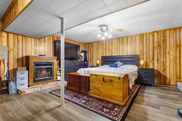 bedroom with ceiling fan, wooden walls, and hardwood / wood-style floors