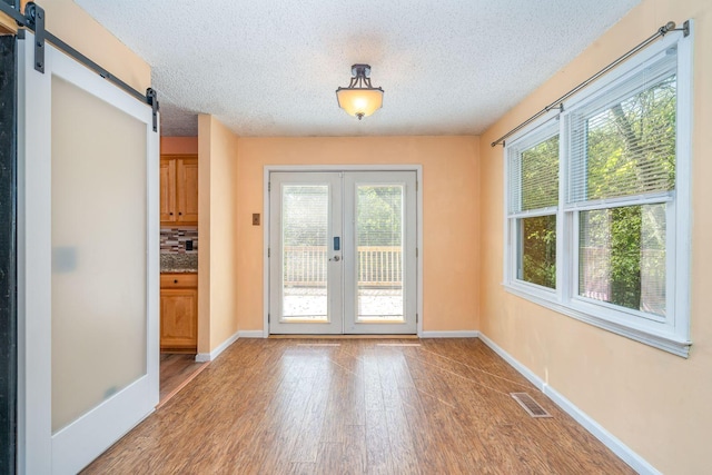 entryway featuring hardwood / wood-style floors, a barn door, a textured ceiling, and french doors