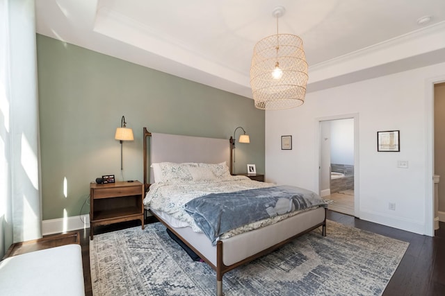 bedroom with a chandelier, ensuite bath, a tray ceiling, and dark hardwood / wood-style flooring