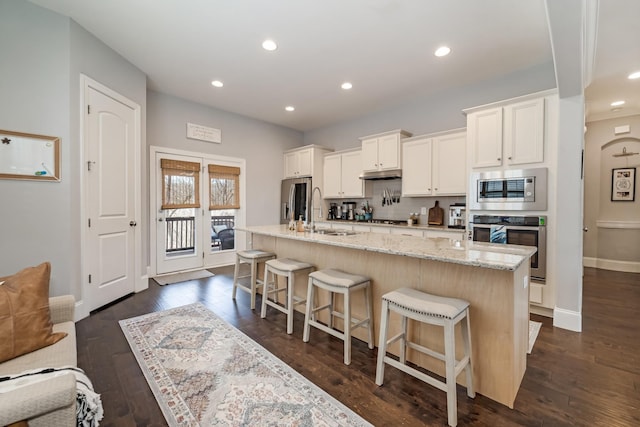 kitchen with stainless steel appliances, sink, a kitchen island with sink, and a breakfast bar area