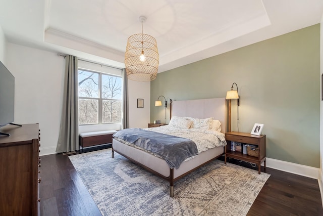 bedroom with a notable chandelier, dark hardwood / wood-style flooring, and a tray ceiling