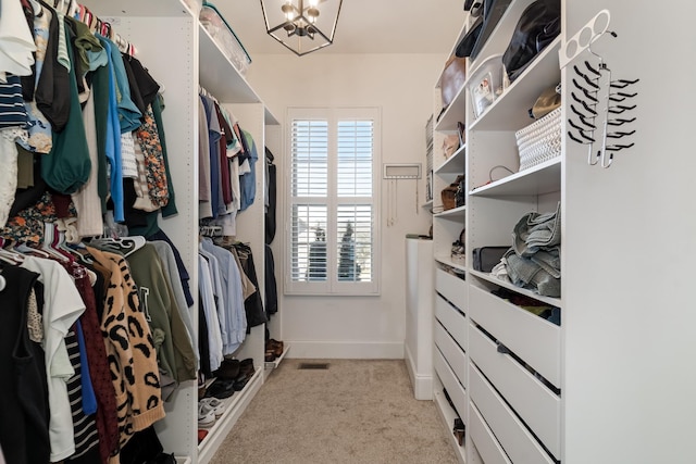 walk in closet featuring light carpet and a chandelier